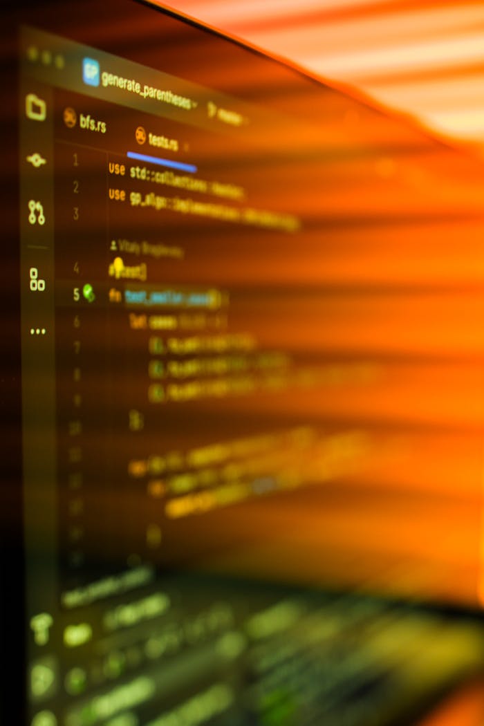 our-services-02 Vibrant, motion-blurred view of programming code on a computer screen with an abstract orange glow.
